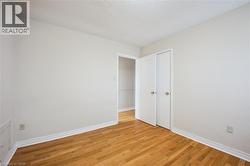 Room featuring wood-finish flooring, white baseboards, and neutral wall paint - 