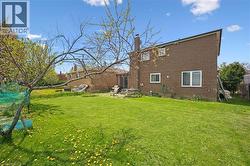 Expansive lawn area with mature trees and brick exterior - 