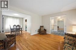 Open-concept living area featuring hardwood flooring, light-toned wall finishes, and a framed opening to a dining space with a window - 
