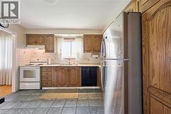 Functional kitchen featuring wood-finish cabinetry, white tile backsplash, and a window above the sink - 