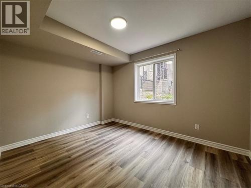 Room featuring wood-finish flooring, neutral wall paint, white baseboards, and a window with white trim - 44 Walnut Street Unit# E01, Kitchener, ON - Indoor Photo Showing Other Room