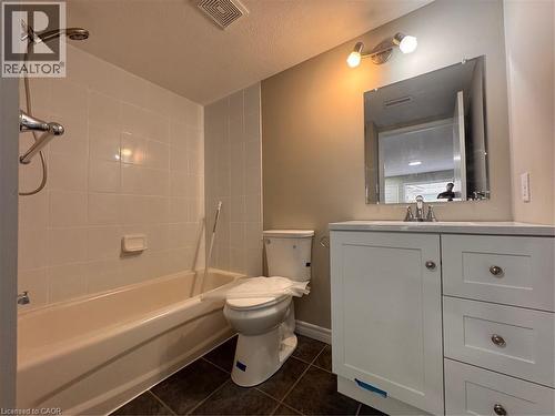 Bathroom featuring a white vanity with integrated sink, a framed mirror, and a tub with white tile surround - 44 Walnut Street Unit# E01, Kitchener, ON - Indoor Photo Showing Bathroom