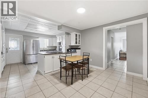 Spacious kitchen featuring white cabinetry, dark countertops, stainless steel refrigerator, and tiled flooring - 2934 Baker Road, Niagara Falls, ON - Indoor Photo Showing Kitchen