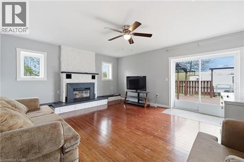 Living area featuring wood-finish flooring, a white stone-clad fireplace with a dark mantel and hearth, and a ceiling fan with integrated lighting - 2934 Baker Road, Niagara Falls, ON - Indoor Photo Showing Living Room With Fireplace