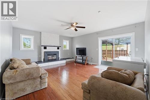 Living area with wood-finish flooring, a fireplace featuring a stone hearth and white mantel, and a ceiling fan with light fixture - 2934 Baker Road, Niagara Falls, ON - Indoor Photo Showing Living Room With Fireplace