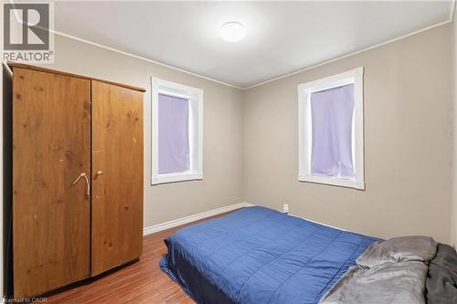 Room with wood-finish flooring, two windows with white trim, and neutral wall tones - 2934 Baker Road, Niagara Falls, ON - Indoor Photo Showing Bedroom
