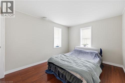 Bedroom featuring hardwood flooring, two windows with blinds, white trim, and light-toned walls - 2934 Baker Road, Niagara Falls, ON - Indoor Photo Showing Bedroom