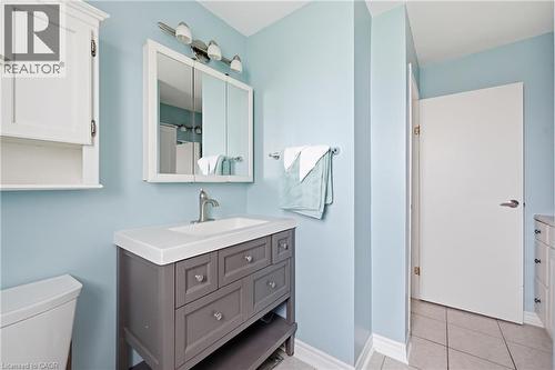 Bathroom featuring a gray vanity with an integrated sink, a white medicine cabinet, and a wall-mounted light fixture - 2934 Baker Road, Niagara Falls, ON - Indoor Photo Showing Bathroom
