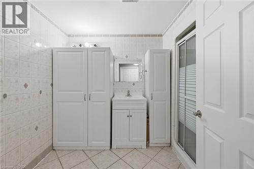 Tiled bathroom with a white vanity featuring a basin sink and mirrored medicine cabinet - 2934 Baker Road, Niagara Falls, ON - Indoor