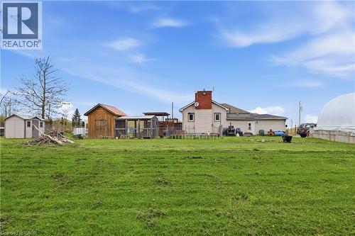 Expansive green field area with a primary residence featuring a brick chimney, accompanied by multiple outbuildings including a wood-sided shed, several smaller sheds, and an additional structure with - 2934 Baker Road, Niagara Falls, ON - Outdoor