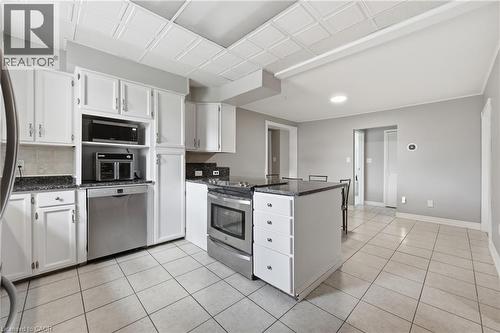 Kitchen featuring white cabinetry, dark stone-finish countertops, stainless steel appliances, and tiled flooring - 2934 Baker Road, Niagara Falls, ON - Indoor Photo Showing Kitchen