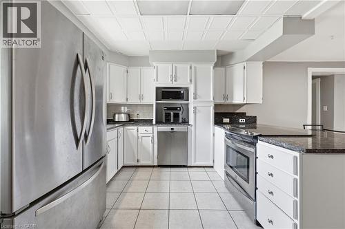 Kitchen featuring white cabinetry, dark stone countertops, and stainless steel appliances including a refrigerator, dishwasher, and built-in oven - 2934 Baker Road, Niagara Falls, ON - Indoor Photo Showing Kitchen With Stainless Steel Kitchen