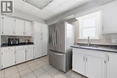 Kitchen featuring white cabinetry, granite-style countertops, stainless steel refrigerator, and tiled flooring - 2934 Baker Road, Niagara Falls, ON - Indoor Photo Showing Kitchen
