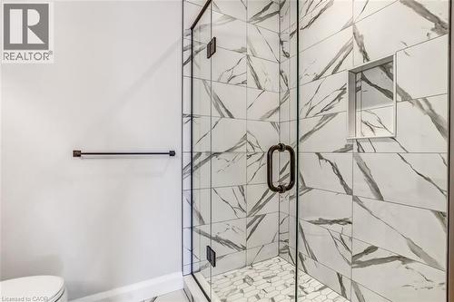 Photos from a similar model for illustration purposes only. Glass-enclosed shower with black-framed door, white and gray patterned wall tiling, and hexagonal floor tiling - 7 Boer Drive, Simcoe, ON - Indoor Photo Showing Bathroom