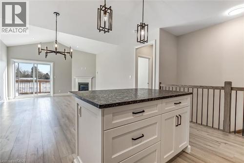 Photos from a similar model for illustration purposes only. Kitchen island with white cabinetry and dark countertop, complemented by pendant lighting - 7 Boer Drive, Simcoe, ON - Indoor