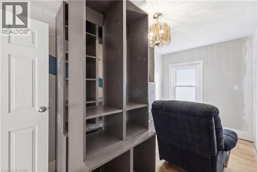 Built-in shelving with multiple compartments, a white paneled door, a clear glass chandelier, a single window, and light wood-finish flooring - 54 Evan Street, Welland, ON - Indoor Photo Showing Office