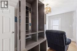 Built-in shelving with multiple compartments, a white paneled door, a clear glass chandelier, a single window, and light wood-finish flooring - 