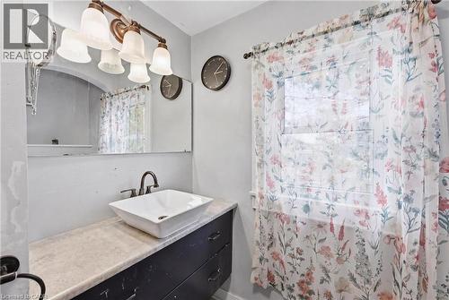 Bathroom featuring a vessel sink with a dark bronze faucet, a vanity with ample storage, and a large wall-mounted mirror - 54 Evan Street, Welland, ON - Indoor Photo Showing Bathroom
