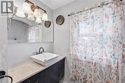 Bathroom featuring a vessel sink with a dark bronze faucet, a vanity with ample storage, and a large wall-mounted mirror - 