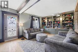 Living area with built-in shelving, wood-finish flooring, exposed ceiling beams, and a decorative glass-paneled door - 
