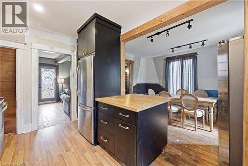 Kitchen island with wood-finish countertop, stainless steel refrigerator, and recessed lighting - 54 Evan Street, Welland, ON - Indoor Photo Showing Kitchen