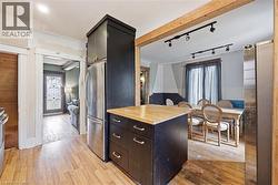 Kitchen island with wood-finish countertop, stainless steel refrigerator, and recessed lighting - 