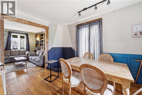 Wood-finish flooring extends through the dining area, featuring a decorative blue wainscoting and track lighting - 54 Evan Street, Welland, ON - Indoor