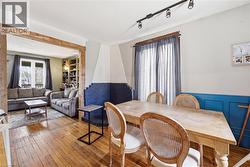 Wood-finish flooring extends through the dining area, featuring a decorative blue wainscoting and track lighting - 