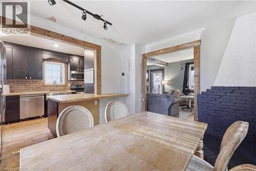Dining area with a natural wood-finish table and chairs, featuring a fireplace with black-painted brick, and a natural wood-finish pass-through to the kitchen - 54 Evan Street, Welland, ON - Indoor