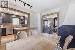 Dining area with a natural wood-finish table and chairs, featuring a fireplace with black-painted brick, and a natural wood-finish pass-through to the kitchen - 