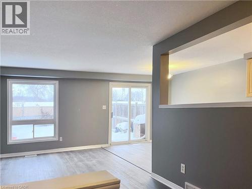 Living area featuring wood-finish flooring, a large window, and a sliding glass door providing exterior access - 193 Prosperity Drive, Kitchener, ON - Indoor Photo Showing Other Room
