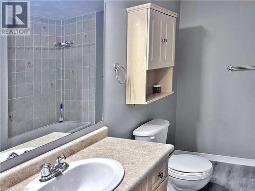 Bathroom featuring a shower-tub combination with tile surround, a vanity with an integrated sink, a wall-mounted medicine cabinet, and wood-finish flooring - 193 Prosperity Drive, Kitchener, ON - Indoor Photo Showing Bathroom