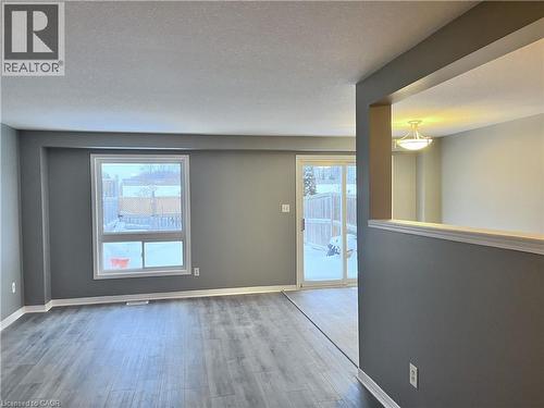 Living area featuring wood-finish flooring, a large window, and a sliding glass door - 193 Prosperity Drive, Kitchener, ON - Indoor Photo Showing Other Room