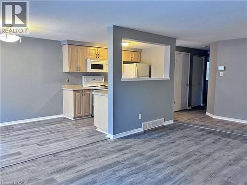 Kitchen and living area featuring wood-finish flooring, light gray wall paint, and recessed lighting - 193 Prosperity Drive, Kitchener, ON - Indoor Photo Showing Kitchen