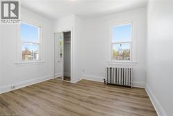 Bright interior space featuring wood-finish flooring, white walls, and two windows with white trim - 