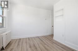 Interior room featuring wood-finish flooring, white painted walls, and a window with white trim - 