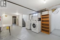 Basement utility area featuring a washer and dryer, exposed ceiling pipes, and a concrete floor - 