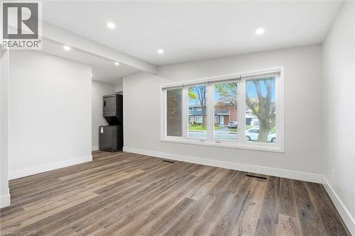 Spacious room featuring wood-finish flooring, white baseboards, and light gray walls - 16 Ronaldshay Avenue, Hamilton, ON - Indoor Photo Showing Other Room