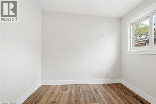 Bright room featuring wood-finish flooring, white baseboards, a white window frame, and a sliding window - 16 Ronaldshay Avenue, Hamilton, ON - Indoor Photo Showing Other Room