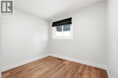 Room featuring wood-finish flooring, white baseboards, a single window, and light neutral wall paint - 16 Ronaldshay Avenue, Hamilton, ON - Indoor Photo Showing Other Room