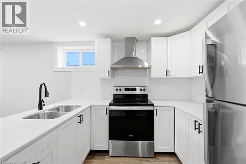 Modern kitchen featuring white shaker-style cabinetry, stainless steel appliances, a subway tile backsplash, a double basin sink with a matte black faucet, and recessed lighting - 16 Ronaldshay Avenue, Hamilton, ON - Indoor Photo Showing Kitchen With Double Sink