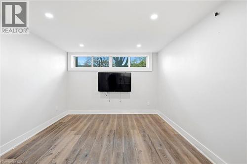 Spacious room featuring wood-finish flooring, white baseboards, and crisp white walls - 16 Ronaldshay Avenue, Hamilton, ON - Indoor Photo Showing Other Room