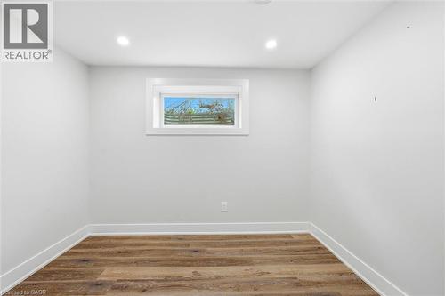 Room featuring wood-finish flooring, white baseboards, a white-framed window, recessed ceiling lighting, and light-toned walls - 16 Ronaldshay Avenue, Hamilton, ON - Indoor Photo Showing Other Room