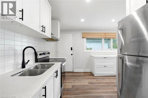 Modern kitchen featuring white cabinetry with matte black hardware, light-toned countertops, and a subway tile backsplash - 16 Ronaldshay Avenue, Hamilton, ON - Indoor Photo Showing Kitchen With Double Sink With Upgraded Kitchen