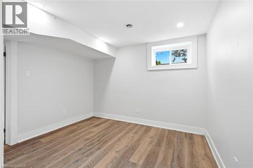 Light-filled room featuring wood-finish flooring, recessed lighting, a window with white trim, and a white baseboard - 16 Ronaldshay Avenue, Hamilton, ON - Indoor Photo Showing Other Room