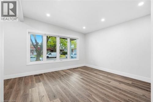 Bright interior space featuring a large picture window, recessed ceiling lighting, wood-finish flooring, white walls, and white baseboards - 16 Ronaldshay Avenue, Hamilton, ON - Indoor Photo Showing Other Room