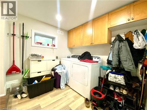 Laundry area featuring wood-finish flooring, a window, and overhead cabinetry - 358 Dundas Street E, Hamilton, ON - Indoor Photo Showing Laundry Room
