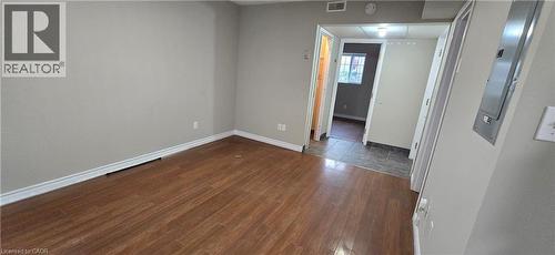Spacious interior featuring wood-finish flooring, light grey walls, white baseboards, and a white ceiling - 274 E Highland Road E Unit# 10, Kitchener, ON - Indoor Photo Showing Other Room