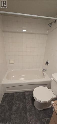 Bathroom featuring a white tub, chrome fixtures, white subway tile surround, and dark-toned floor tiles - 274 E Highland Road E Unit# 10, Kitchener, ON - Indoor Photo Showing Bathroom