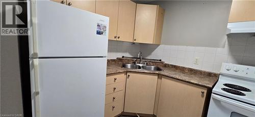 Kitchen featuring a white top-freezer refrigerator, double basin stainless steel sink, light wood-finish cabinetry, and white tile backsplash - 274 E Highland Road E Unit# 10, Kitchener, ON - Indoor Photo Showing Kitchen